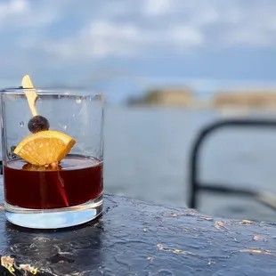 a glass of alcohol with an orange garnish