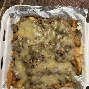 a tray of fries covered in cheese