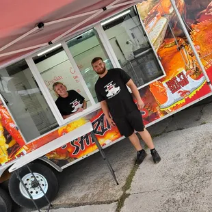 two men standing in front of a food truck