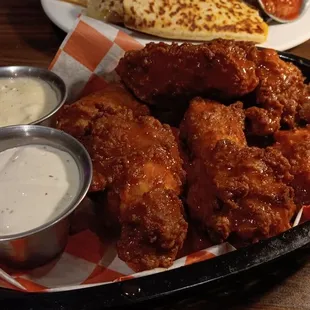 a basket of chicken wings and dips