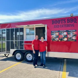 two people standing in front of a food truck