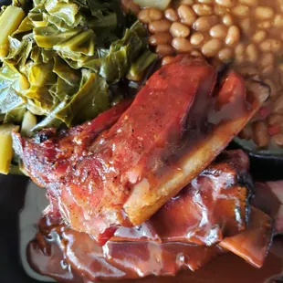 a plate of meat, beans, and greens