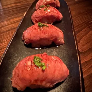 four pieces of meat on a black plate