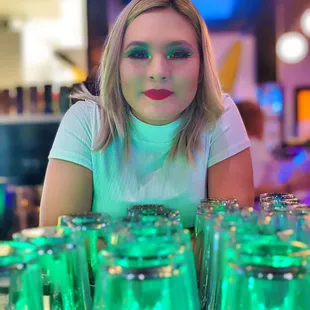 a woman sitting at a bar with green glasses
