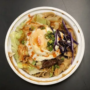 a bowl of noodles with an egg on top