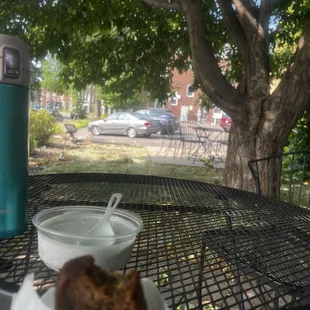 I am sitting under a tree at a table outside with some banana bread and Chia pudding