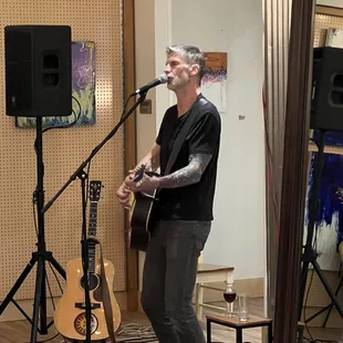 a man playing a guitar and singing into a microphone
