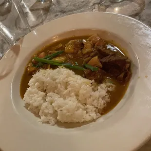 a white plate with rice and meat