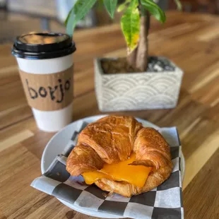 a croissant sandwich and a cup of coffee