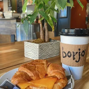 a croissant sandwich and a cup of coffee