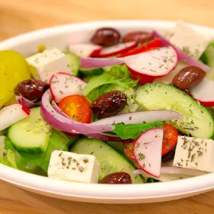 a bowl of salad with cucumbers, radishes, olives, radishes, and