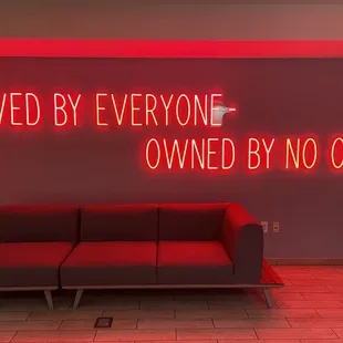 a red neon sign that reads loved by everyone - owned by no one