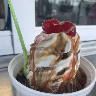 Caramel, peanut butter sundae with cherries on top.