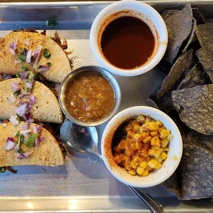 Beef birria taco plate (sheet pan, actually) with dipping sauce, whole kernel elotes, plus chips &amp; salsa.