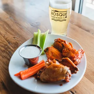 a plate of wings, carrots, celery, and a glass of beer