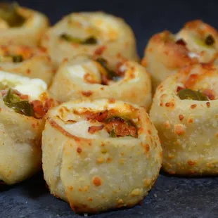 a close up view of several rolls of pizza with cheese and jalapenos