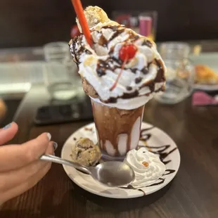 a hand holding a spoon and a cup of ice cream