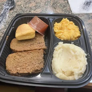 a tray of meatloaf, mashed potatoes, and bread