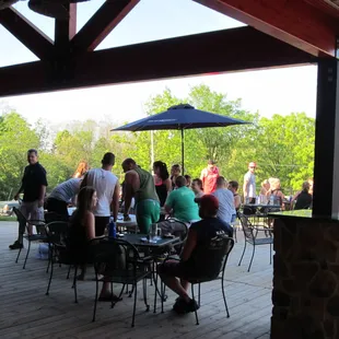 a group of people sitting at tables under an umbrella