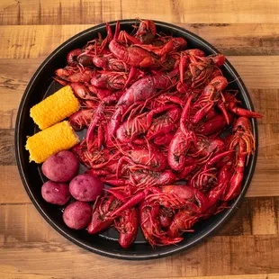 a plate of craws, potatoes, corn