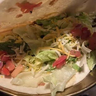 a taco with lettuce, tomatoes and cheese