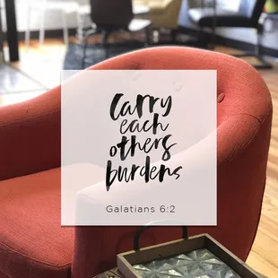 a red chair with a tray on it and the words carry each other's burden