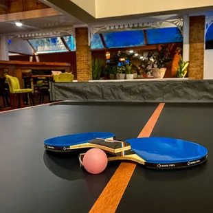 two ping pong paddles and a ball on a ping pong table