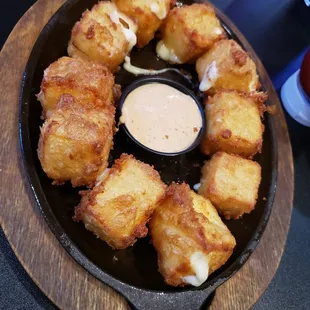 a cast iron skillet with tater tots and dipping sauce