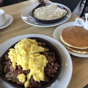 Corned Beef hash with scrambled eggs Skillet. Biscuits and gravy in the background.