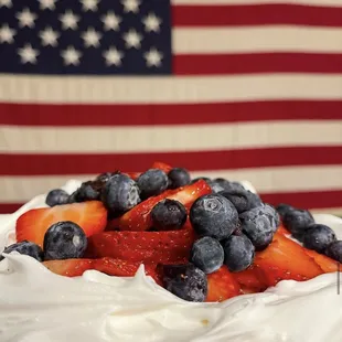 a dessert with whipped cream, strawberries, and blueberries