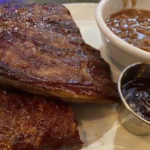 a plate of ribs and a bowl of sauce