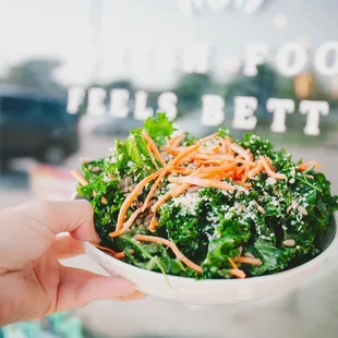 a person holding a bowl of salad
