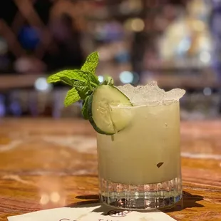 a cocktail with a cucumber garnish