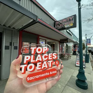 a person holding up a sign that says top places to eat sacramento area