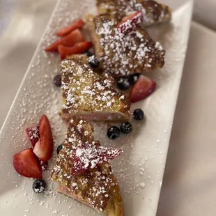 a plate of french toast with strawberries and blueberries