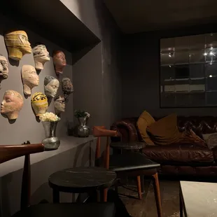a living room with a leather couch and a collection of masks on the wall