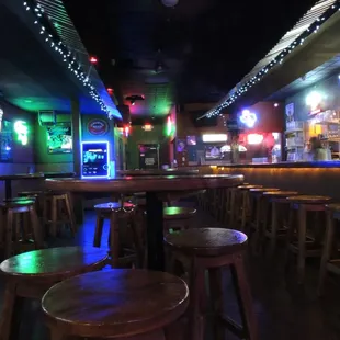 a bar with stools and neon lights