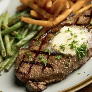 Steak and fries dinner with "cowboy" butter melted on top of steak, served with green beans and fries.