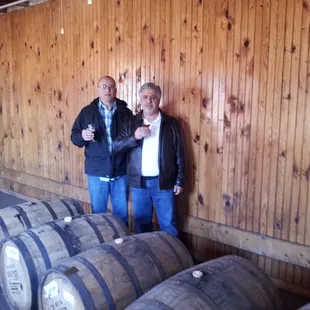 two men standing next to barrels