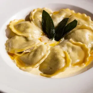 a plate of ravioli with sage leaves