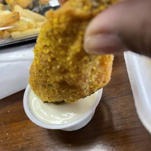 a hand holding a piece of fried food