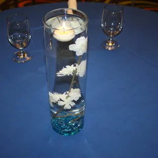 a table with a blue tablecloth and a vase with white flowers