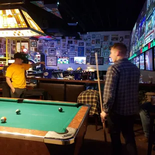 two men playing pool in a bar