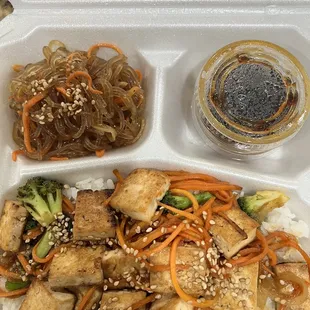 a take out container with rice, broccoli, and tofu