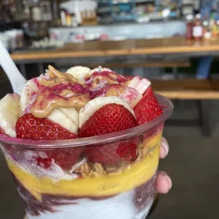 Blue coconut, Açaí, and mango with honey almond granola, strawberries, bananas, coconut, chia, peanut butter, honey, and pitaya powder