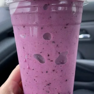 a hand holding a purple smoothie