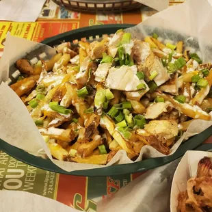a basket of fries with cheese and green onions