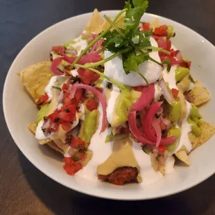 Happy Hour version of Lentil Nachos (spicy lentils, cashew queso, pickled onions, tofu crema &amp; pico on a warm bed of tortilla chips)