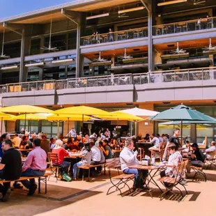 a large group of people sitting at tables under umbrellas