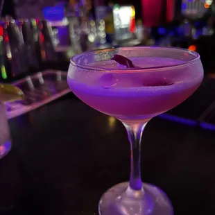 a purple cocktail in a coupe glass